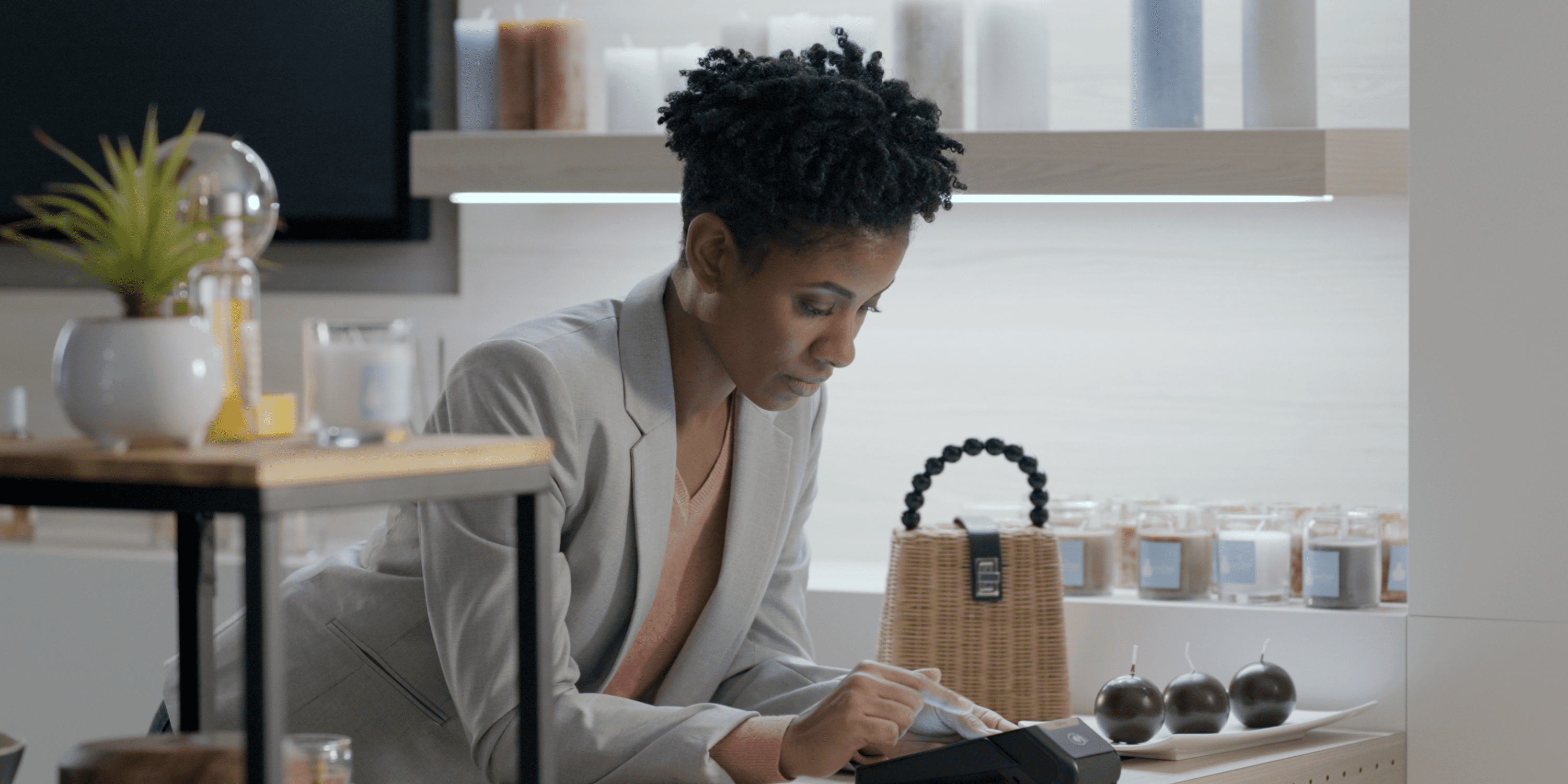 Femme professionnelle effectuant une transaction sur terminal moderne dans une boutique élégante et lumineuse.