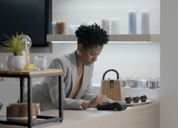Femme professionnelle effectuant une transaction sur terminal moderne dans une boutique élégante et lumineuse.