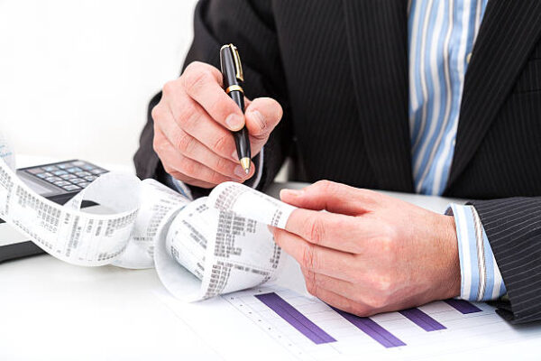 Comptable vérifiant des reçus et graphiques financiers sur un bureau professionnel.