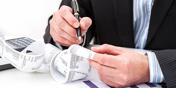 Comptable vérifiant des reçus et graphiques financiers sur un bureau professionnel.
