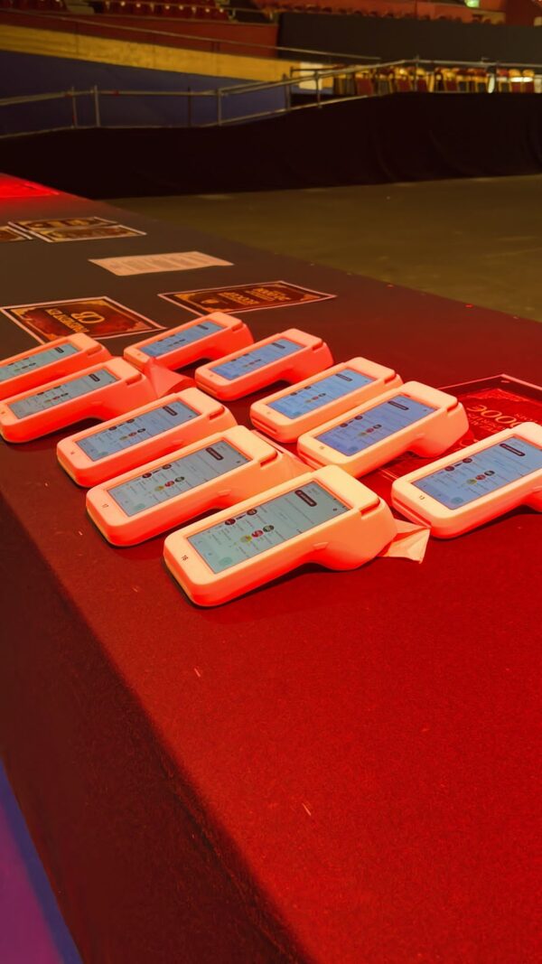 Terminaux électroniques alignés sur table rouge prêts pour un événement technologique à Grenoble.