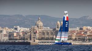 Catamaran français naviguant devant la Cathédrale La Major à Marseille.
