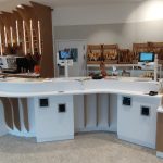 Intérieur de boulangerie moderne avec comptoir en bois clair, pains artisanaux et viennoiseries fraîches.